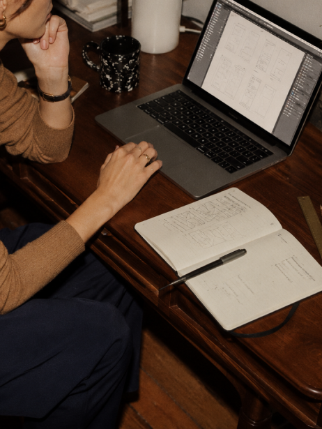Nat trabajando en su escritorio, bocetando wireframes junto al portátil